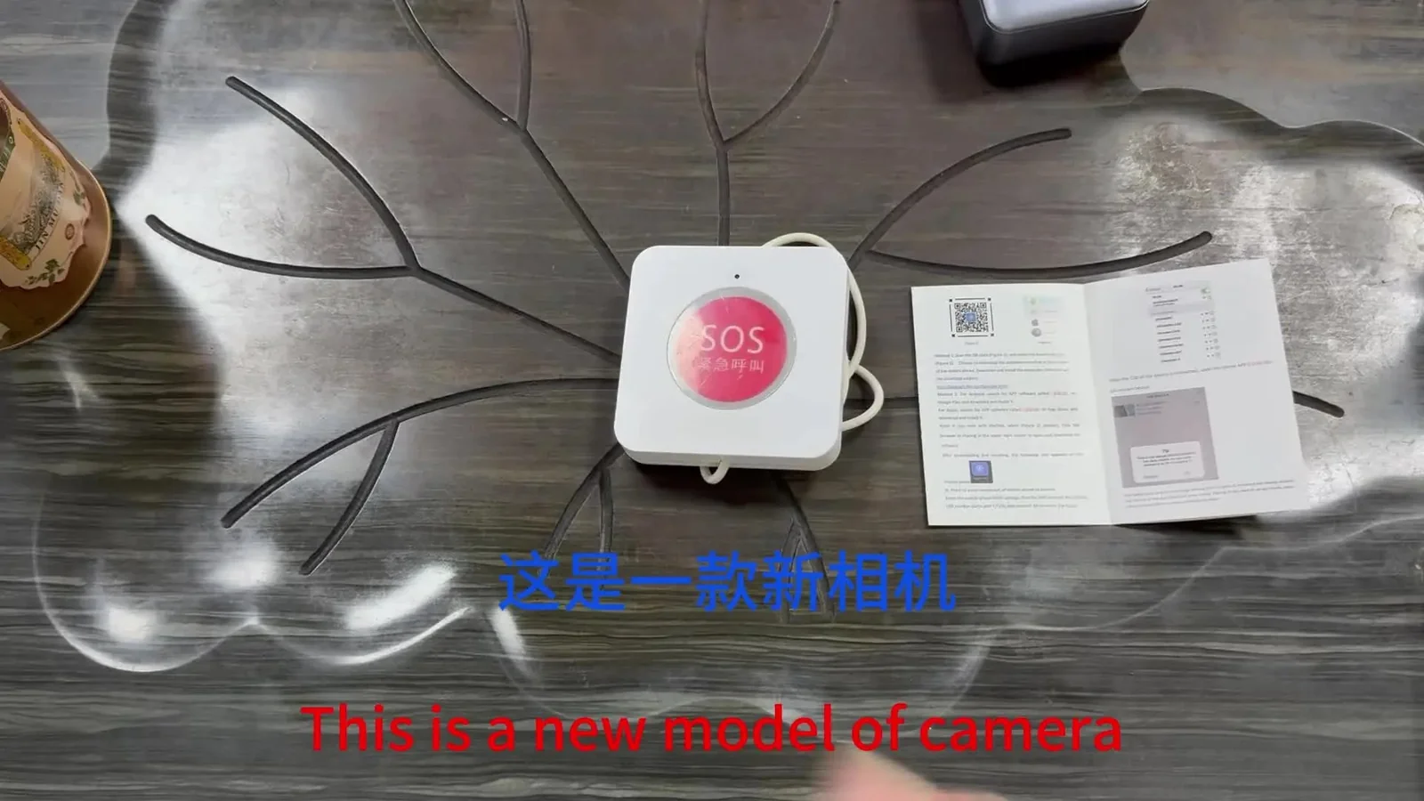 Wall SOS-button–style camera — desk shot with cable